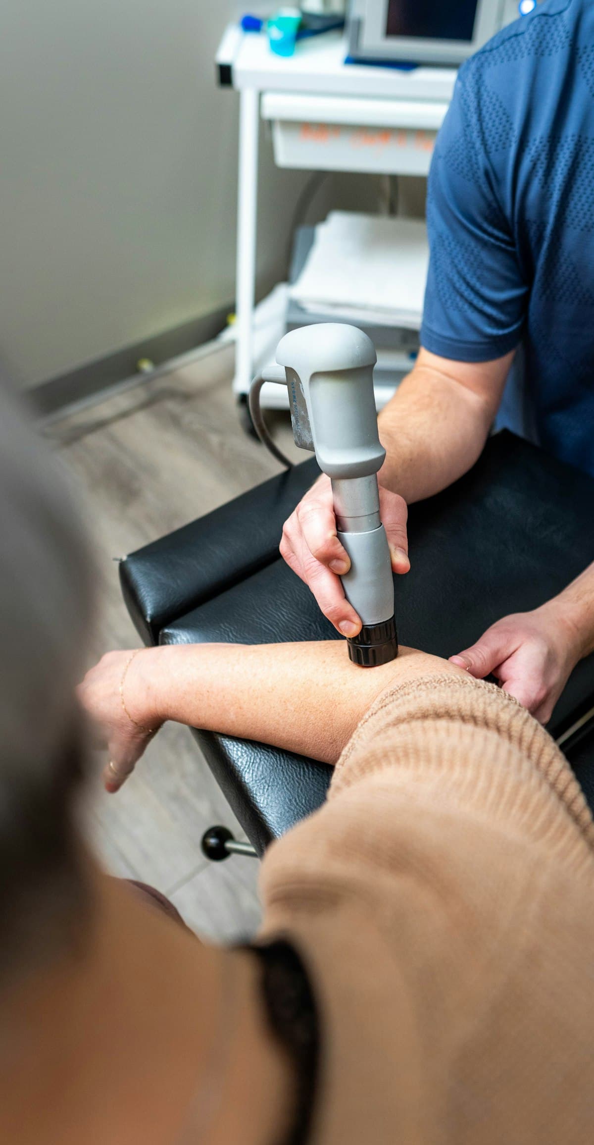 Therapist using a therapy device on a patient's forearm